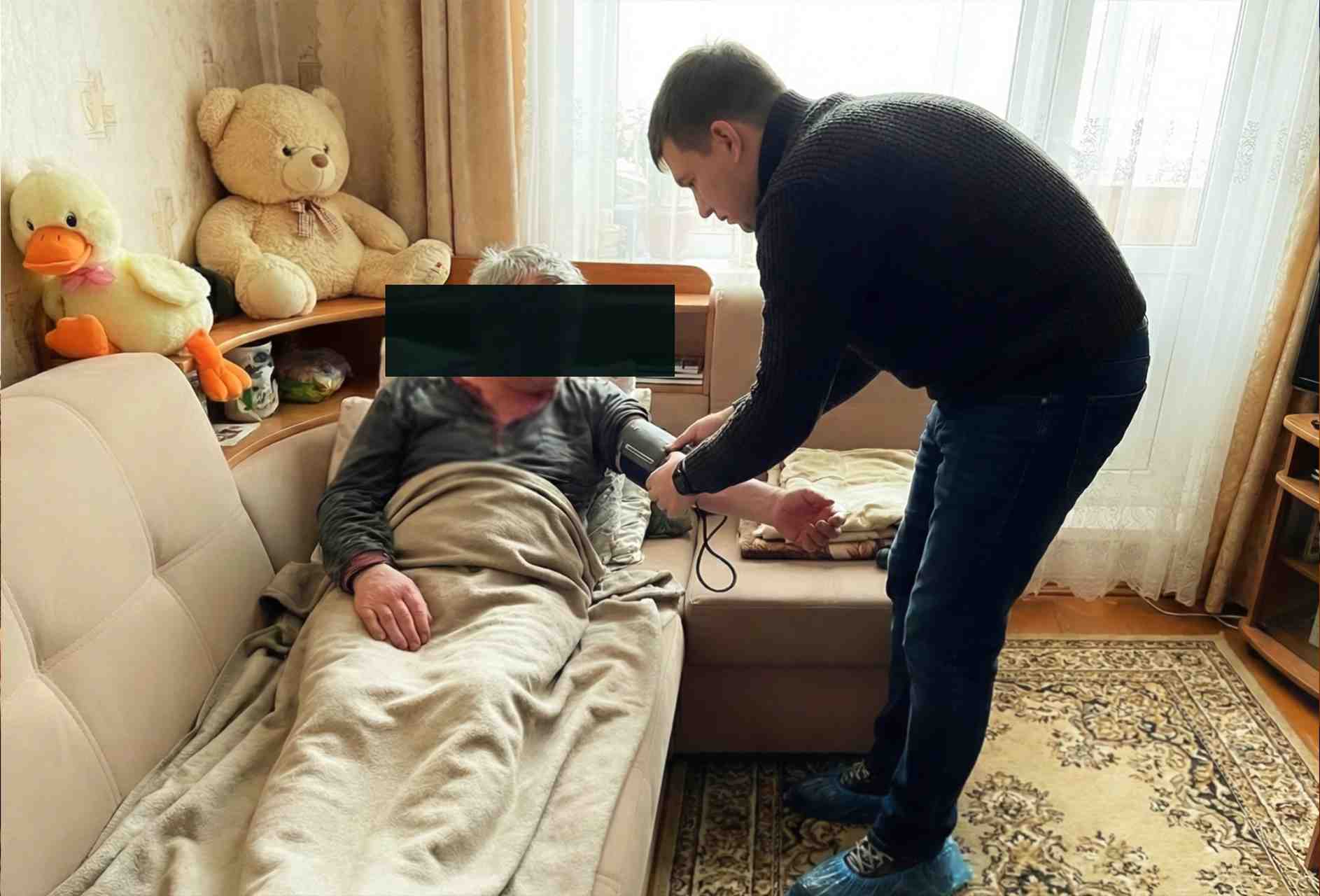 Доктор за столом у больного на кухне делает записи